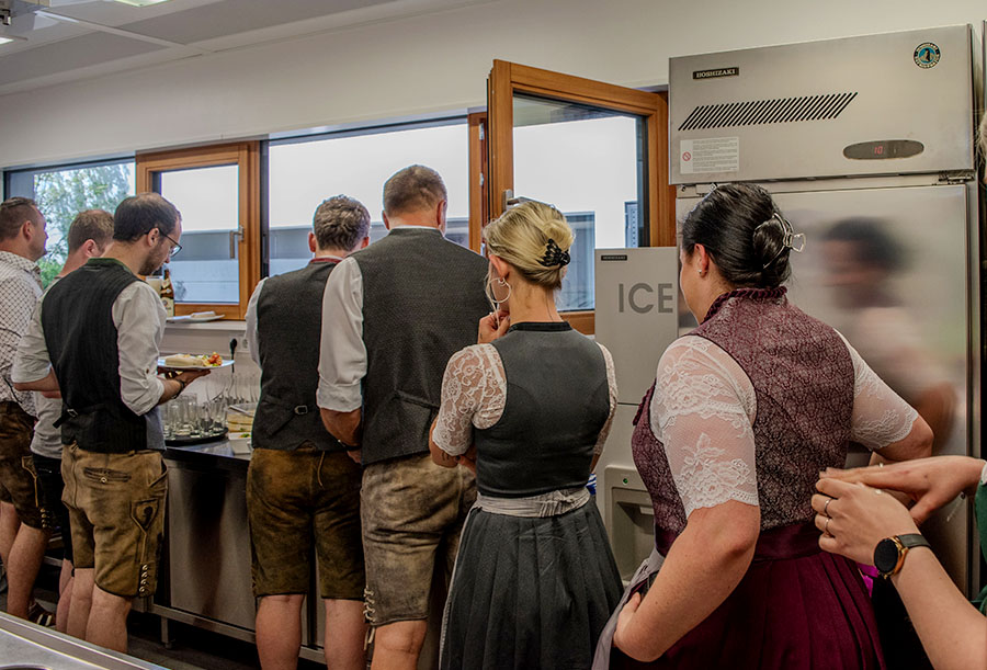 Mitarbeiter stehen am aufgebauten Buffet mit Weißwurst und Salaten