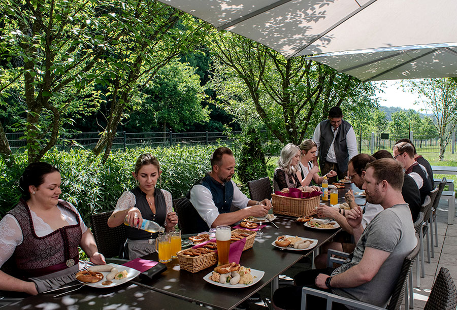 Mitarbeiter essen gemütlich auf der Terrasse die Weißwürste