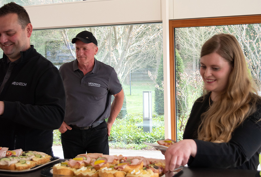 Melanie und Jens nehmen sich lächeln belegte Brötchen vom Tablett