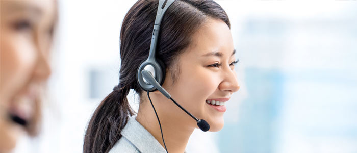 Lächelnde Frau mit Headset und Mikrofonarm telefoniert in einem Call Center