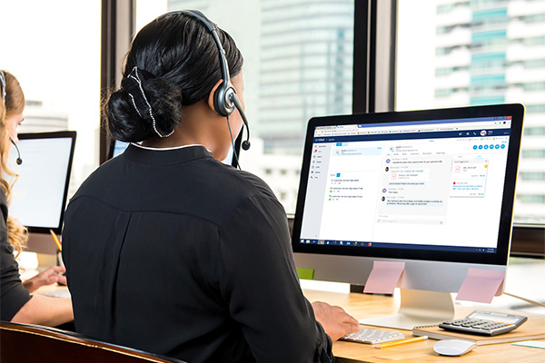 Mehrere Frauen sitzen in einem Büro, telefonieren mit Headsets und arbeiten nebenbei am PC.