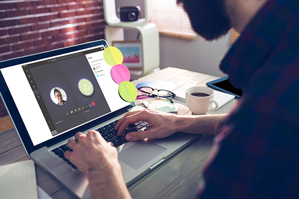 Mann sitzt im Home-Office am Schreibtisch und hat über den Laptop ein Online-Meeting